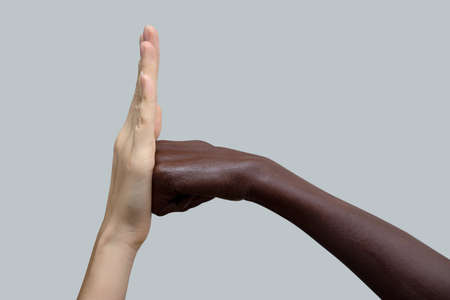 Two hands, black and white. A black fist strikes a white palm.The concept of inter-racial friendship and respect, the fight against racism. Close-up, selective focus.の写真素材