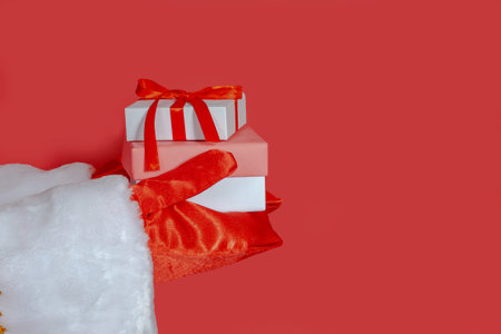 Santa Claus holds out his hands with gifts on a red isolated background. Close-up, selective focus, banner, copy space. The Concept Of A Happy Christmas.の写真素材