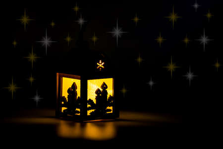 Christmas decorations made of natural material, wooden carved house on a dark background. Close-up, selective focus, star glareの写真素材