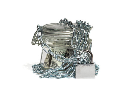 Dollar bills in a glass jar, closed on a chain with a lock. Money in bank. The concept of home...