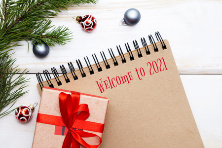 Welcome to 2021.Photo of an empty notebook on a spiral, with brown sheets, a new years gift, Christmas decorations. Selective focus, flat lay.の写真素材