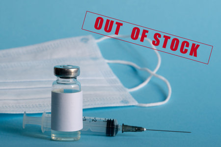 A medicine ampoule, a medical syringe, and disposable masks are close-up on a blue isolated...