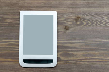 A blank tablet screen in a horizontal position, on a wooden surface. Close-up, top view. A mockup for your ad.の写真素材
