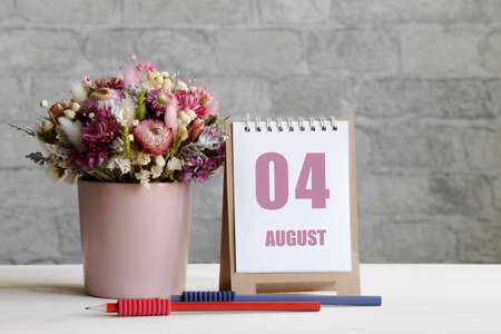 august 04.04th day of the month, calendar date. Delicate bouquet of flowers in a pink vase, two pencils and a calendar with a date for the day on a wooden surface ..の写真素材