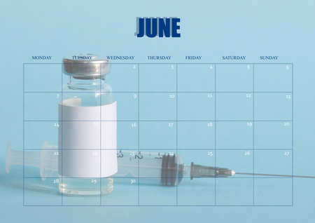 Clean desktop calendar for the month of June, for the doctor. The layout used as the schedule planner. Ampoule with vaccine and tag, medical syringe in the background. All inscriptions are in English.の写真素材