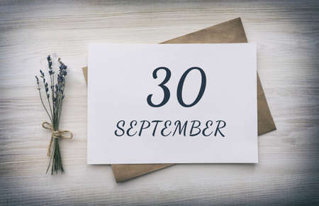 september 30.30th day of the month, calendar date.White blank of paper with a brown envelope, dry bouquet of lavender flowers on a wooden background. Autumn month, day of the year concept.の写真素材