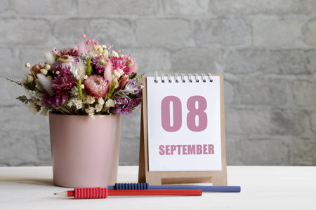 september 08. 08-th day of the month, calendar date.A delicate bouquet of flowers in a pink vase, two pencils and a calendar with a date for the day on a wooden surfaceの写真素材