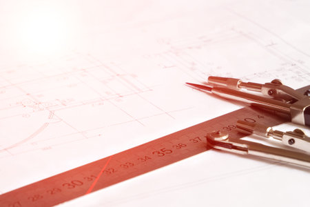 Two compasses and a metal ruler on the background of an architectural plan for the construction of a...