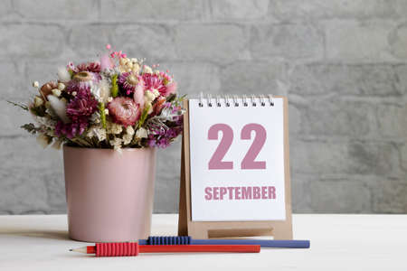 september 22.22-th day of the month, calendar date.A delicate bouquet of flowers in a pink vase, two pencils and a calendar with a date for the day on a wooden surface ..の写真素材