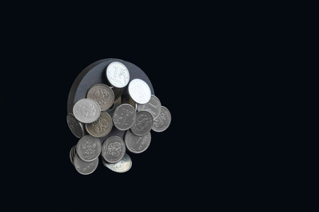 Black round magnet with Russian iron coins levitates in air on dark isolated background. Concept of...
