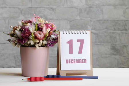 december 17. 17-th day of the month, calendar date.A delicate bouquet of flowers in a pink vase, two pencils and a calendar with a date for the day on a wooden surface ..の写真素材