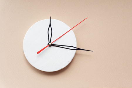 Hands of clock on round wooden dial. Close-up, isolated beige background, copy space.
