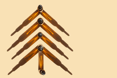 Creative Christmas tree made of packages of glass bottles with dropper lid, with hard shadows on beige background. Concept of Happy New Year in beauty industry. Flat lay, copy space.の写真素材