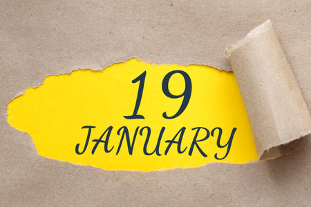 january 19. 19th day of the month, calendar date.Hole in paper with edges torn off. Yellow background is visible through ragged hole. Winter month, day of the year concept.の写真素材