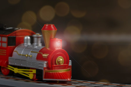 Toy Christmas locomotive on background of garland of bokeh lights. Concept of celebrating Christmas...
