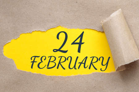 february 24. 24th day of the month, calendar date.Hole in paper with edges torn off. Yellow background is visible through ragged hole.Winter month, day of the year conceptの写真素材