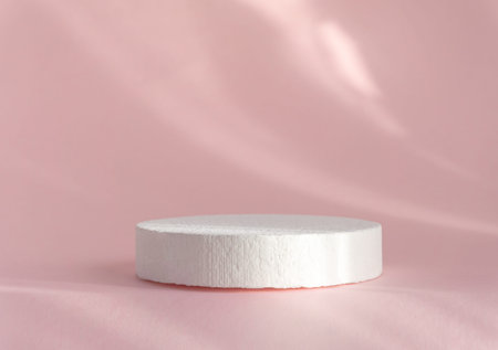 White round polystyrene showcase on abstract textured rose background, in rays of sunlight. 3D...