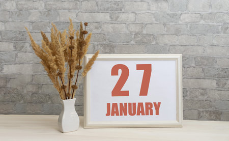 january 27. 27th day of month, calendar date. White vase with ikebana and photo frame with numbers...