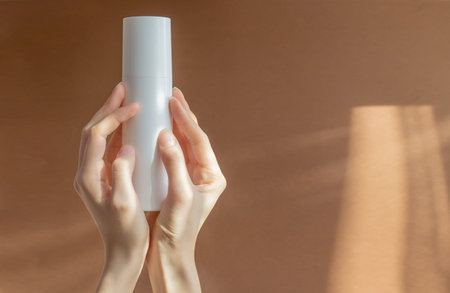 Two female hands hold unmarked white mock-up of aerosol bottle with foam for washing. Close-up,...