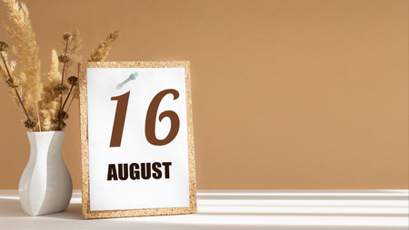 August 16. 16th day of month, calendar date.White vase with dead wood next to cork board with numbers. White-beige background with striped shadow. Concept of day of year, time planner, summer month.の写真素材