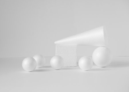 Composition of various 3d geometric shapes in white. Polystyrene balls, cube, cone, on isolated light background. Concept of visual aids, podiums.の写真素材