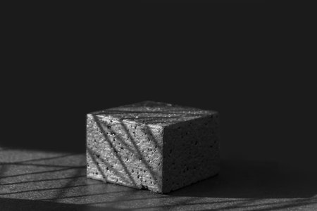 Black square geometric platform in sunlight with shadows. Concept of 3d podium for presentations of packaging and cosmetics. Close up, copy space, monochrome image.の写真素材