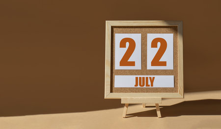 July 22th. Day 22 of month, Calendar date. Cork board, easel in sunlight on desktop. Close-up, brown background. Summer month, day of year concept.の写真素材