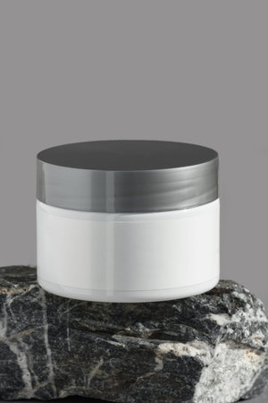 White jar with grey lid of cream on a marble stone stand. Stylish look of the product, mock up, grey background.の写真素材