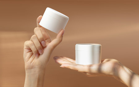 Women's hands hold unmarked white cans with tightening facial cream. Anti age healthy dry skin care beauty therapy concept.の写真素材