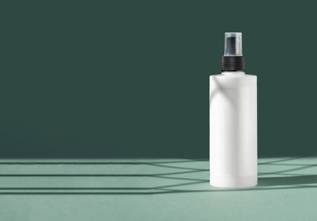White unmarked plastic spray bottle on green background with Light on wall. Mockup container for lotion, hand gel, spray, Copy space banner,の写真素材