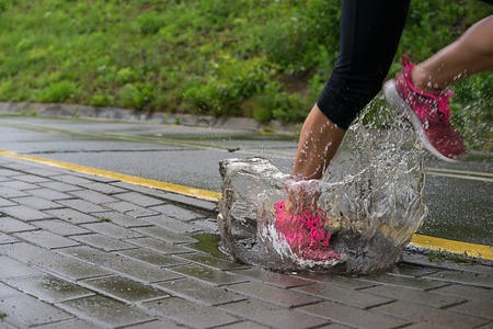 Single runner running in rain and making splash in puddleの写真素材