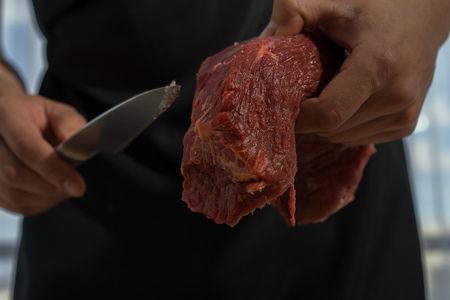 Butcher cutting beef in the kitchenの写真素材