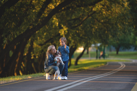 happy young mother with adorable kids and dog walking in park