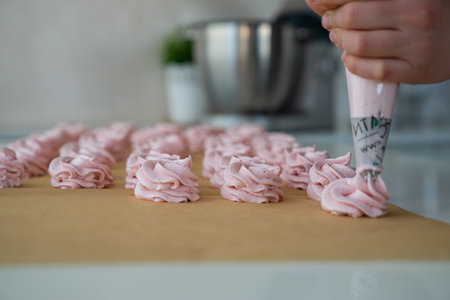 Close up hands of the chef with confectionery bag cream to parchment paper at pastry shop kitchen