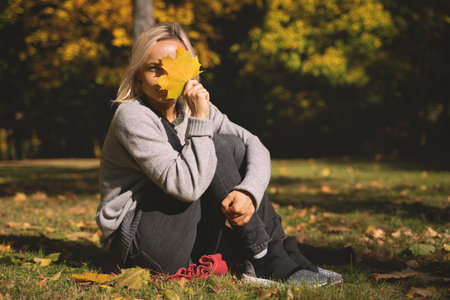Young woman lying in autumn park with leafs.