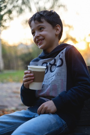 boy holds cup in hands on fallen leaves background. autumn mood beautiful day. Golden fall in still life. Bright Fall image.の写真素材