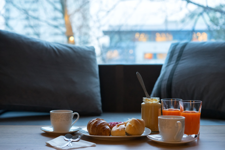 Dark kitchen table with breakfast set. Freshly baked croissant, peanut butter and coffee on rustic wooden board over dark grunge backdropの写真素材