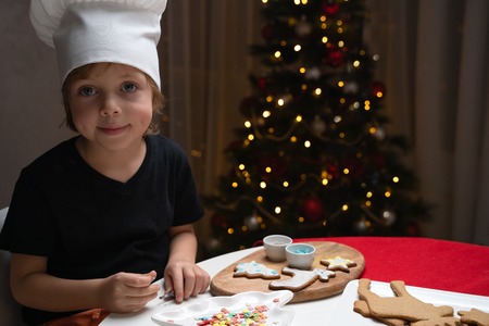 cute happy boy in hat holding delicious ginger cookie and smiling at cameraの写真素材
