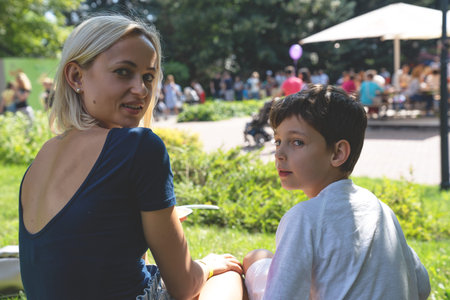 Portrait of mother and son eating street food in the park.