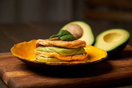 Low Carb Keto Diet Pancakes from almond coconut flour stack on plate with avocado mousse on wooden table background close up view. Selective focus. Ketogenic concept.の写真素材