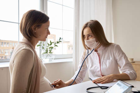 Happy pregnant woman visit gynecologist doctor at hospital or medical clinic for pregnancy consultant. Doctor examine pregnant belly for baby and mother healthcare check up. Gynecology conceptの写真素材