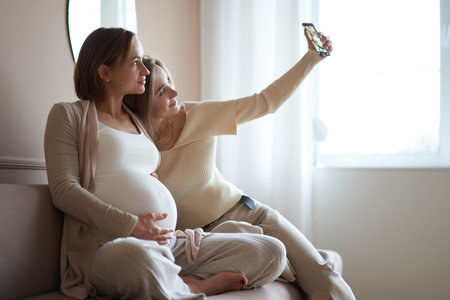 multiethnic girlfriends and happy pregnant woman taking selfie on smartphone . High quality photo.