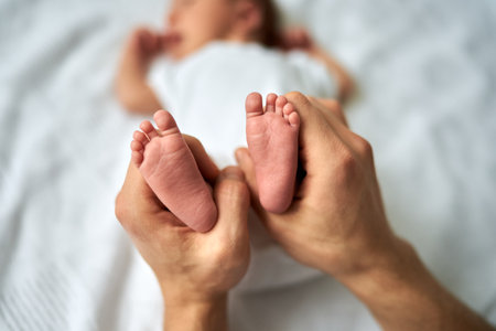 Babys feet in the fathers hands, the foot of a newborn baby, a little baby lies in the crib.の写真素材