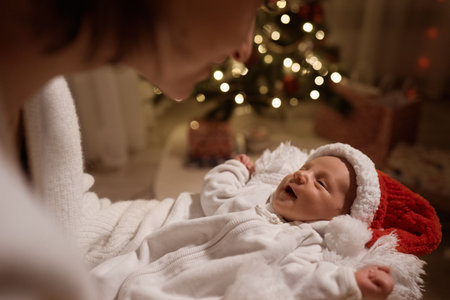 Happy young mother posing with newborn son under Christmas treeの写真素材