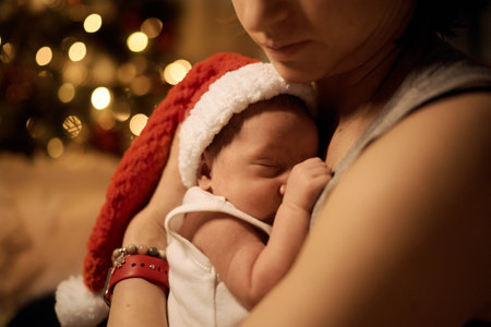 Happy young mother posing with newborn son under Christmas treeの写真素材