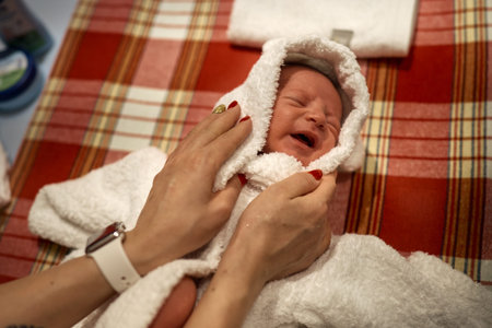 Mother holding little baby wrapped in towel after bathの写真素材