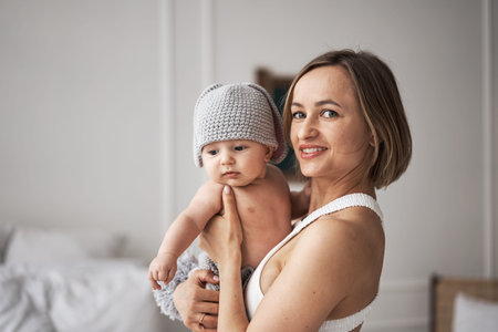 Mother in white dress holding a baby boy in a bunny costume and play with himの写真素材