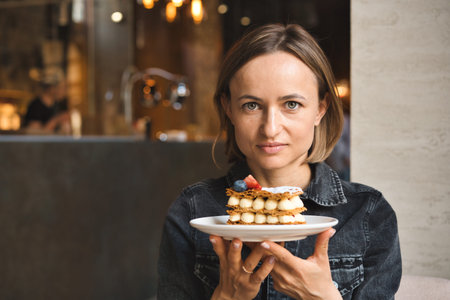 A beautiful caucasian woman holding and showing a plate with dessert in cafe