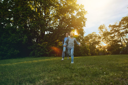 Two brother boys playing outdoors in park at sunset time