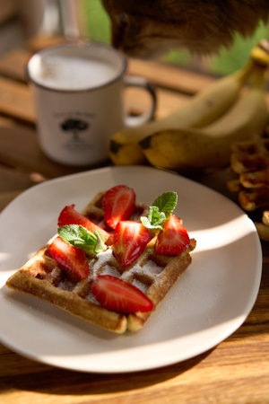 Closeup view of breakfast belgium waffles with strawberry and banana with mint on wooden background